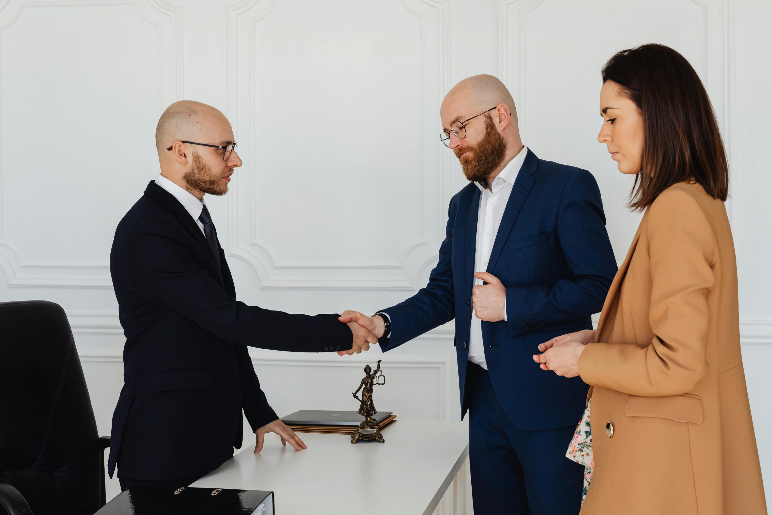 divorce lawyer shaking hands with a male client as his spouse stands next to him
